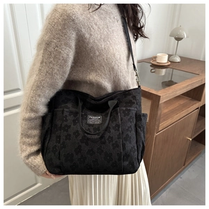 Detail view of black jacquard tote bag featuring floral pattern and adjustable strap
