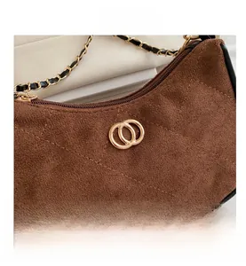 Detail of brown quilted suede underarm bag with gold metal buckle and chain strap