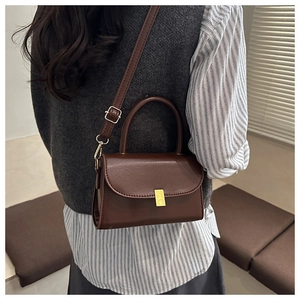 Détail d'un sac bandoulière marron foncé avec boucle dorée et finition en cuir PU lisse