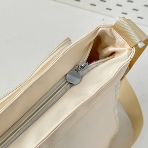 Detail of metal zipper and woven shoulder strap on beige minimalist canvas bag