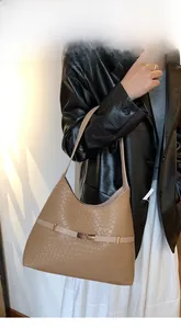 Detail of khaki woven texture shoulder bag with metal buckle on black leather jacket outfit