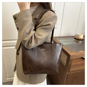 Detail of vintage brown leather tote bag with gold lettering and slim shoulder handles