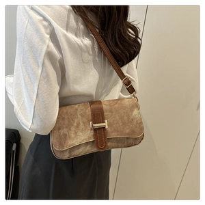 Détail du sac sous le bras marron vintage avec fermoir doré porté par un mannequin en intérieur