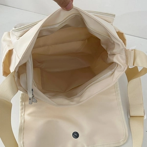 Detail view of large capacity interior with zip pocket and magnetic closure for white messenger bag