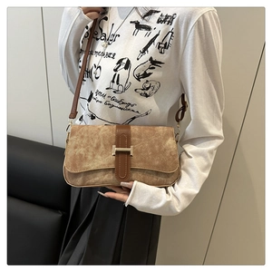 Détail d'un sac bandoulière en daim marron avec une boucle en métal en forme de H vintage