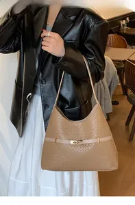 Detail of light brown woven texture hobo bag with gold buckle on shoulder