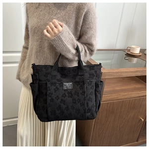 Detail of black multi-pocket canvas tote with floral texture and fashion label