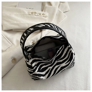 Detail view of mini zebra print handbag interior with smooth metal zipper and leather strap