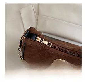 Detail of smooth gold zipper and metallic logo on brown suede shoulder bag