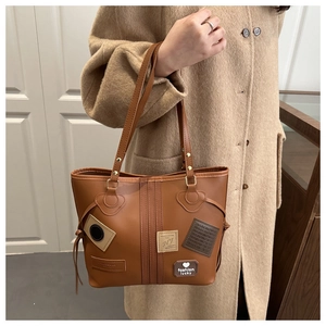 Detail view of brown tote bag with decorative fashion patches and heart embroidery