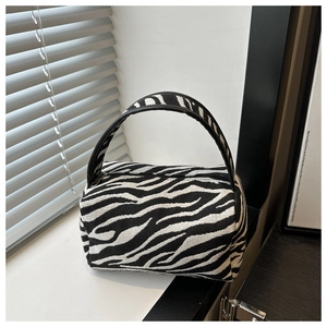 Detail shot of zebra print fabric and black leather handle on a mini pillow bag