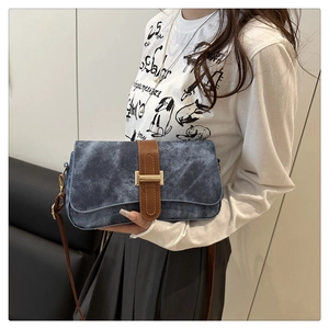 Détail de la texture bleu délavé et de la boucle dorée en H sur le sac rétro élégant