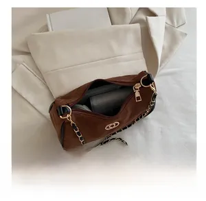 Detail view of brown suede shoulder bag capacity with golden logo and chain strap