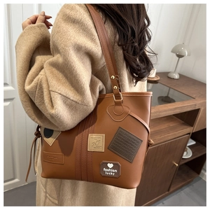 Close-up of brown leather tote bag with vintage patches and adjustable shoulder strap