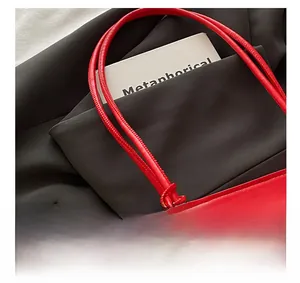 Detail view of red leather tote bag showing fine texture and reinforced stitching work