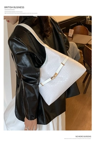 Detailed view of woven texture and gold clasp on a white shoulder tote bag worn by model