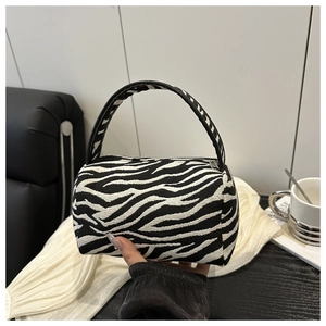 Detail view of zebra print canvas handbag with a sturdy top handle and zipper closure