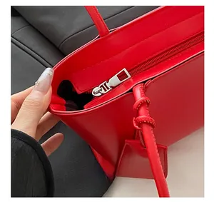 Detailed close-up of the smooth zipper closure on a red leather vintage tote bag