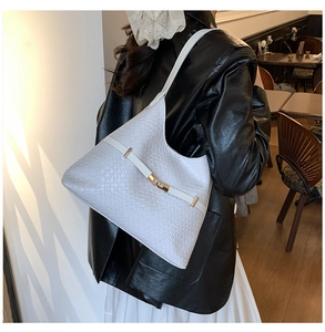 Detail of woven texture white leather tote bag with elegant gold metal buckle closure