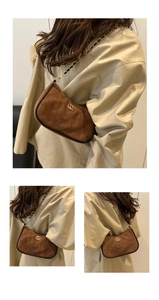 Detail of brown suede underarm bag with quilted stitching and golden metal buckle