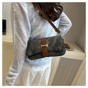 Détail du sac sous le bras en daim gris avec bandoulière en cuir brun et boucle dorée