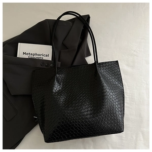Detailed view of large black tote bag with elegant faux crocodile skin embossed texture