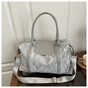 Detail of silver pleated fabric travel bag with adjustable strap and golden hardware