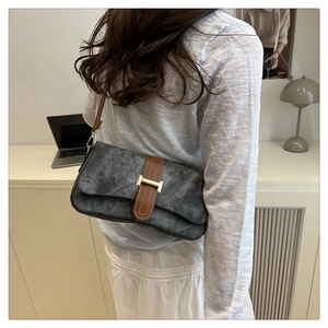 Détail du sac gris foncé avec bandoulière en cuir marron et boucle dorée en métal