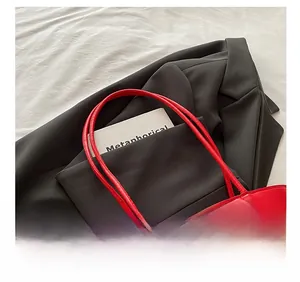 Detail shot of the comfortable red leather shoulder strap and stitching on the tote bag