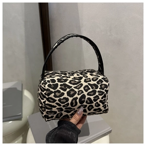 Close-up of leopard print makeup bag with textured fabric and black glossy handle