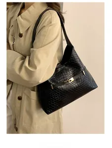 Close-up of the black woven leather texture and golden twist lock on the shoulder bag