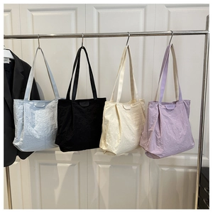Vue détaillée de quatre grands sacs fourre-tout en nylon en bleu clair, noir, crème et lilas