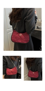 Close-up of burgundy quilted suede underarm bag with gold double-ring buckle and chain strap