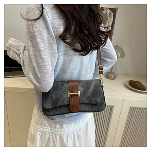 Détail d'un sac sous le bras en daim gris rétro avec fermoir doré porté par un mannequin
