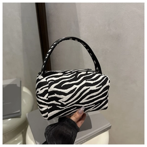 Detailed macro view of zebra pattern knit fabric and black leather handles on Boston bag