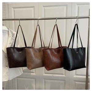 Sacs cabas minimalistes en similicuir en quatre couleurs suspendus sur un support