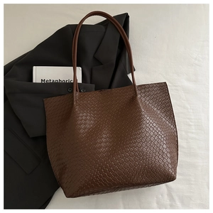 Macro detail of the woven texture and slim leather straps on the coffee tote bag