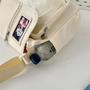 Detail view of cream canvas tote bag showing functional side pocket with water bottle