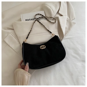 Detailed close-up of black suede underarm bag with gold chain strap and quilted stitching