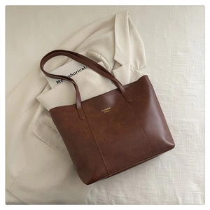 Gros plan sur un sac cabas en simili cuir marron avec texte doré sur tissu blanc