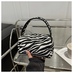 Detail of zebra pattern mini cylinder handbag with fabric texture and black handle