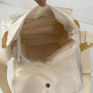 Detail view of large white canvas messenger bag with internal compartments and zip closure
