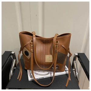 Macro shot of vintage brown PU leather tote bag with stitch details on a black chair