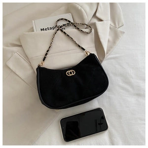 Detail of black suede crescent bag with gold hardware and chain on neutral clothing