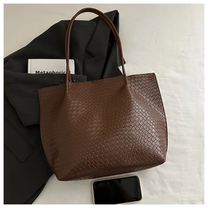 Close-up of brown woven tote bag featuring detailed checkerboard texture and slim straps