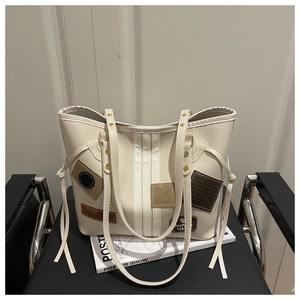 Detail of cream tote bag with brown letter patch and white stripes on black chair