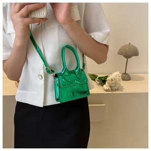 Close-up of mini metallic green crocodile pattern handbag with gold hardware
