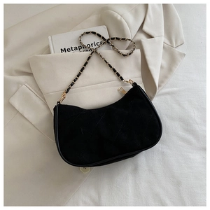 Detail of black quilted crescent hobo bag with gold chain strap on ivory blazer