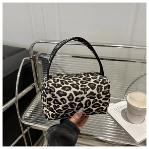 Detail of trendy leopard print mini pillow bag with black handles and top zipper closure