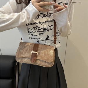 Sac à bandoulière marron vintage avec boucle en H porté par un mannequin dans un décor épuré
